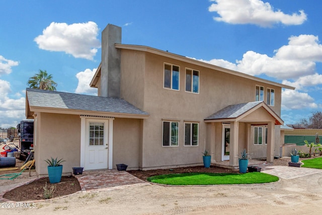 view of front of house featuring roof with shingles, fence, and stucco siding