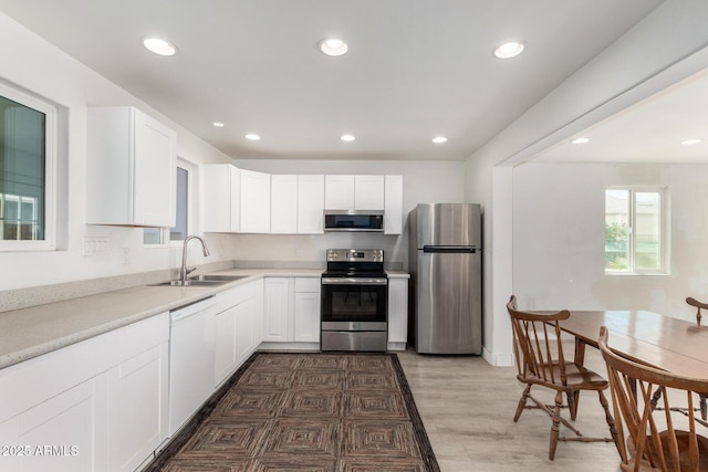 kitchen with white cabinets, appliances with stainless steel finishes, light countertops, a sink, and recessed lighting