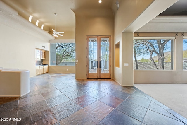 entryway with french doors, ceiling fan, and a high ceiling