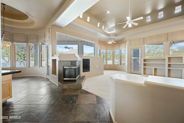 living room featuring a tray ceiling, a wealth of natural light, and ceiling fan