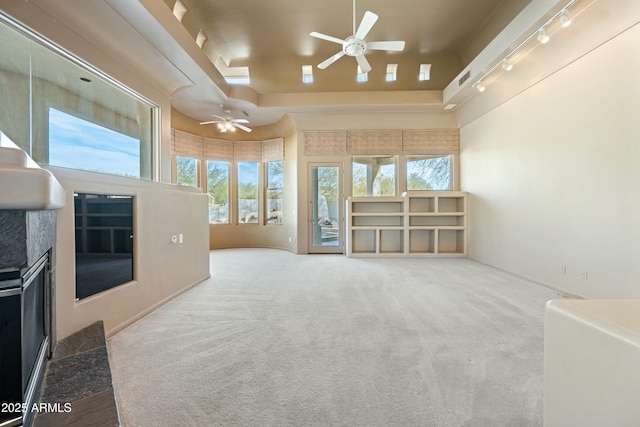 unfurnished living room with track lighting, ceiling fan, and carpet flooring