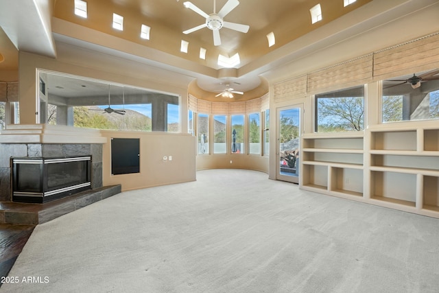 unfurnished living room featuring a fireplace, ceiling fan, and carpet