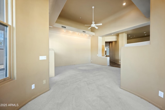 empty room featuring ceiling fan, plenty of natural light, and light carpet