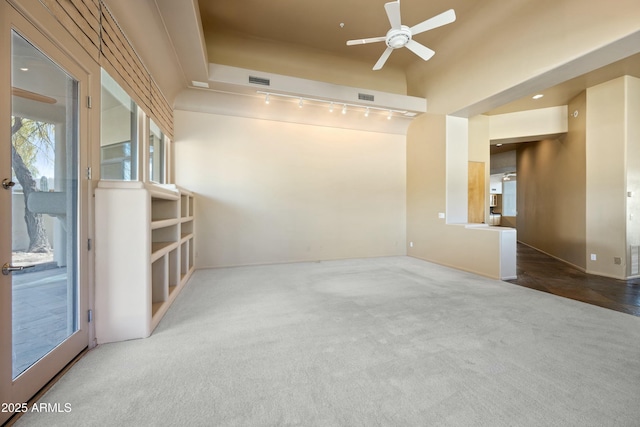 carpeted spare room featuring track lighting and ceiling fan