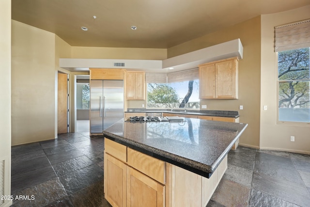 kitchen featuring light brown cabinetry, sink, stainless steel appliances, and a kitchen island