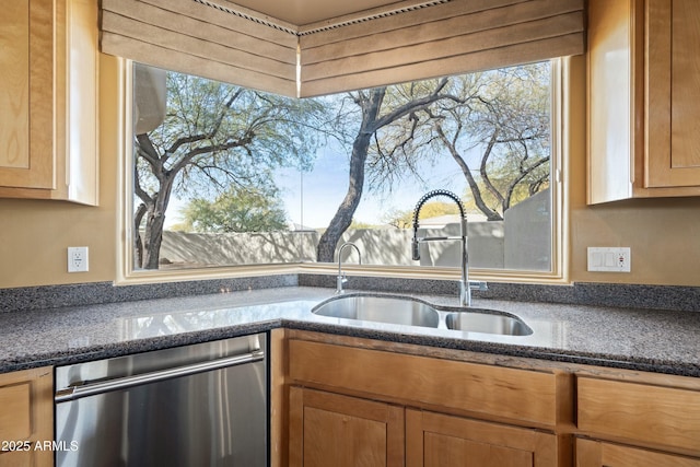 kitchen featuring dishwasher, sink, and dark stone counters