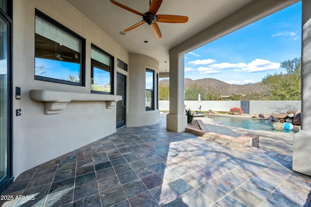 view of patio / terrace with a fenced in pool, ceiling fan, a mountain view, and pool water feature