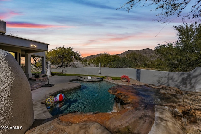 pool at dusk with a mountain view and a patio area