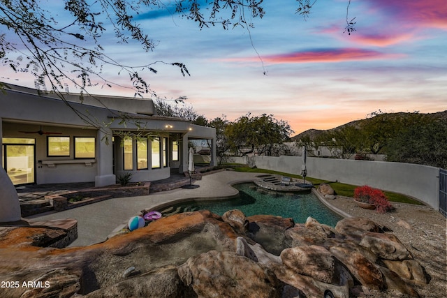 pool at dusk featuring a patio