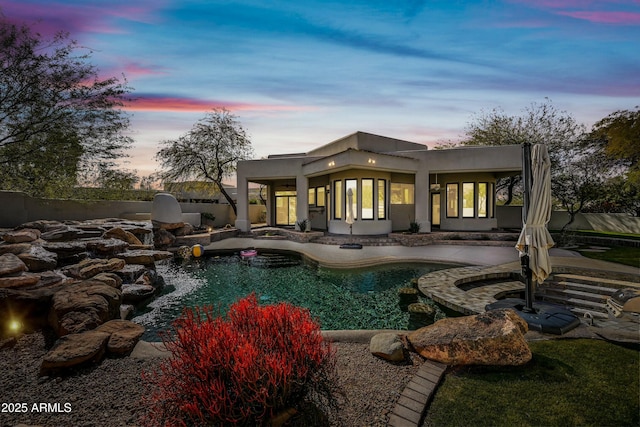 back house at dusk with a fenced in pool and a patio area