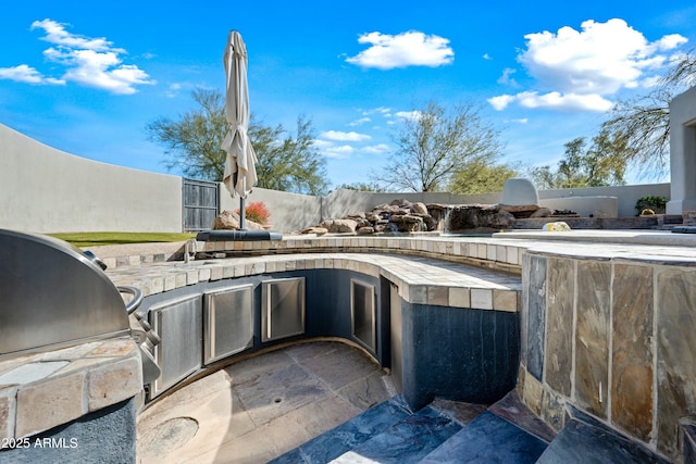 view of patio featuring an outdoor kitchen and a grill