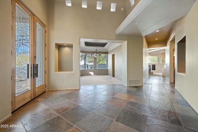 foyer featuring a notable chandelier, plenty of natural light, french doors, and a high ceiling