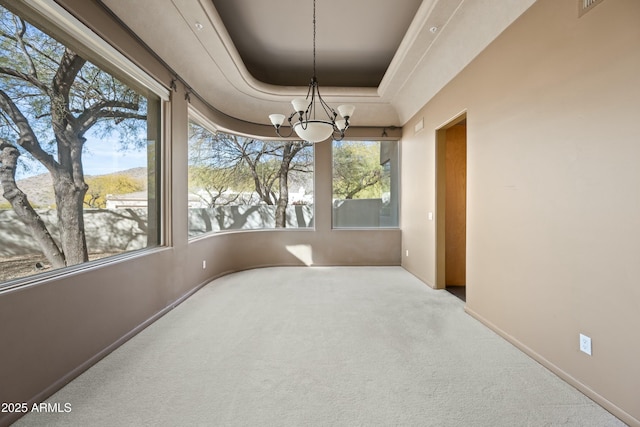 unfurnished sunroom featuring a tray ceiling and a chandelier