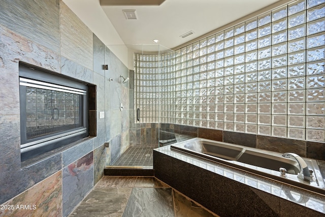 bathroom with tile walls and independent shower and bath