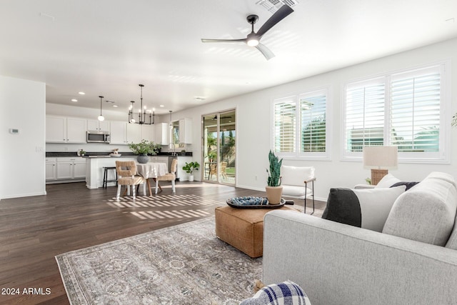 living room featuring plenty of natural light, dark wood-type flooring, and ceiling fan with notable chandelier