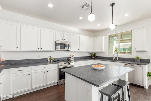 kitchen with hanging light fixtures, sink, dark hardwood / wood-style floors, appliances with stainless steel finishes, and white cabinetry