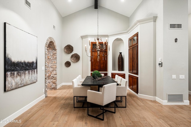 dining area with high vaulted ceiling, beam ceiling, light wood-type flooring, and a chandelier