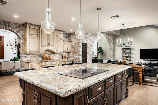 kitchen with dark brown cabinetry, hanging light fixtures, a large island, light wood-type flooring, and cream cabinetry