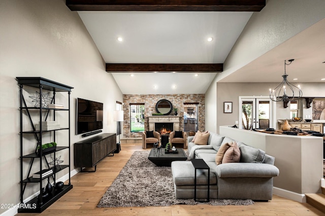 living room featuring a chandelier, a fireplace, light hardwood / wood-style flooring, and lofted ceiling with beams