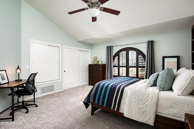 bedroom featuring ceiling fan, lofted ceiling, light colored carpet, and multiple closets