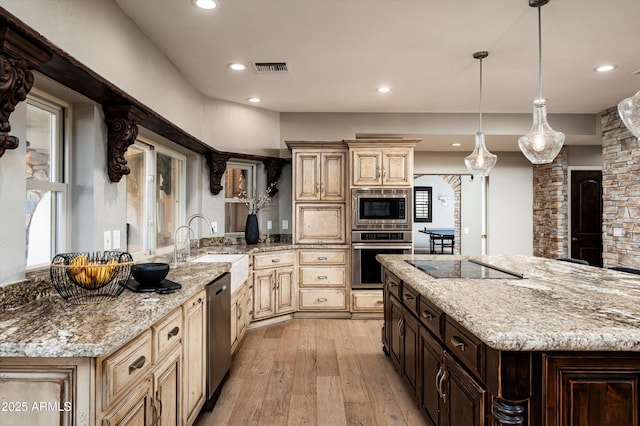 kitchen with light hardwood / wood-style floors, appliances with stainless steel finishes, decorative light fixtures, light stone counters, and dark brown cabinetry