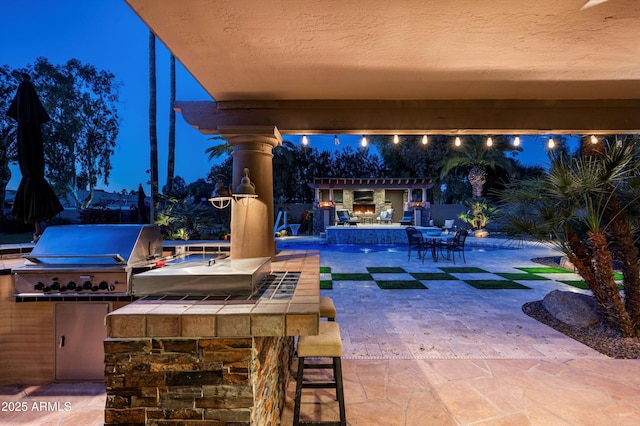 patio terrace at dusk featuring an outdoor bar, grilling area, and area for grilling