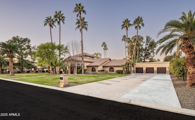 mediterranean / spanish home featuring a yard and a garage