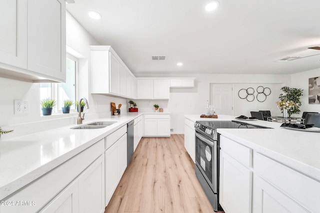 kitchen featuring appliances with stainless steel finishes, light wood-type flooring, sink, and white cabinetry