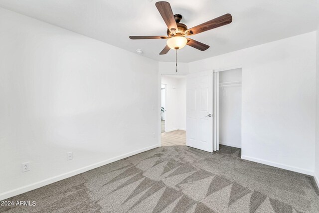 unfurnished bedroom with ceiling fan, light colored carpet, and a closet