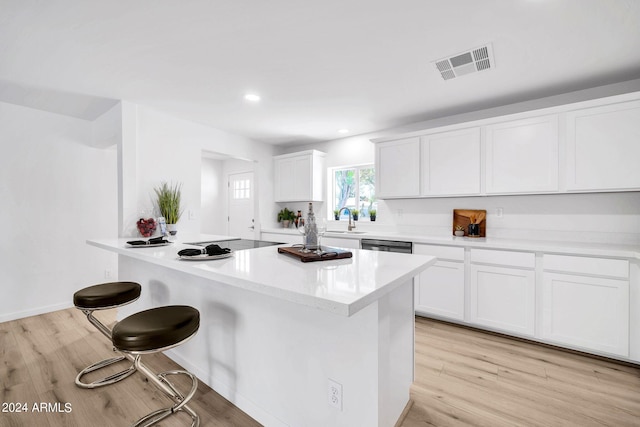 kitchen featuring white cabinets, a breakfast bar area, light hardwood / wood-style floors, and sink