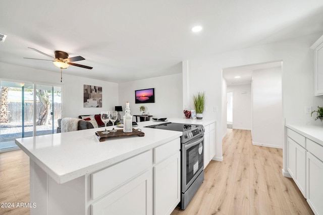 kitchen featuring white cabinetry, a kitchen island, light wood-type flooring, ceiling fan, and electric range