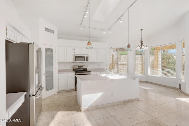 kitchen with white cabinetry, hanging light fixtures, appliances with stainless steel finishes, and a center island with sink