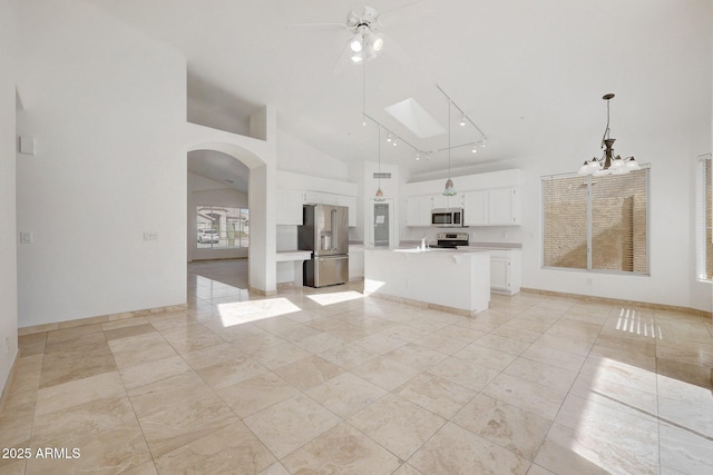 kitchen with a skylight, white cabinetry, stainless steel appliances, pendant lighting, and a center island