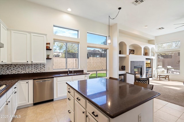 kitchen with white cabinetry, sink, stainless steel dishwasher, and a fireplace