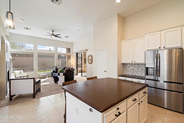 kitchen with light tile patterned flooring, white cabinetry, backsplash, a center island, and stainless steel refrigerator with ice dispenser