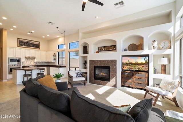 carpeted living room with sink, built in features, and ceiling fan