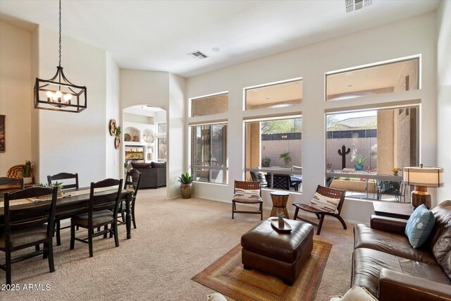 carpeted living room featuring a towering ceiling and a notable chandelier