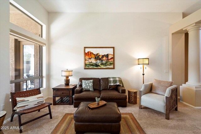 carpeted living room with decorative columns and a towering ceiling