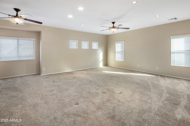 empty room with ceiling fan, light colored carpet, and a healthy amount of sunlight