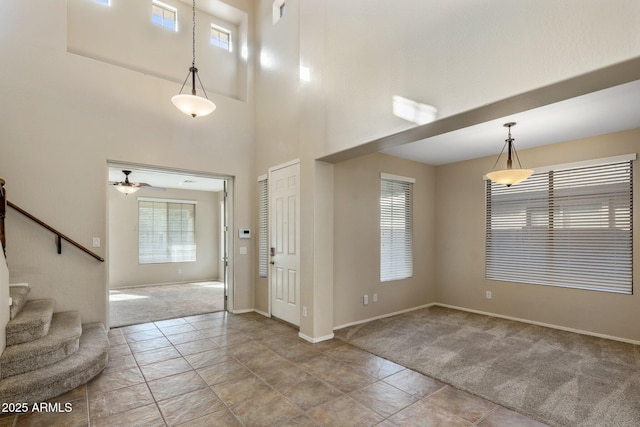 entrance foyer with a towering ceiling, light colored carpet, and ceiling fan