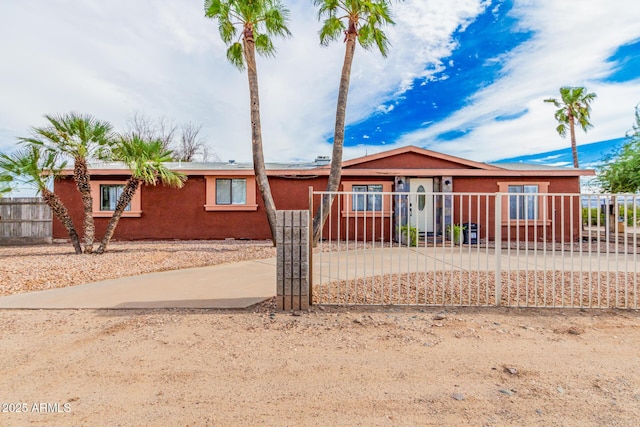 ranch-style home featuring a fenced front yard and stucco siding