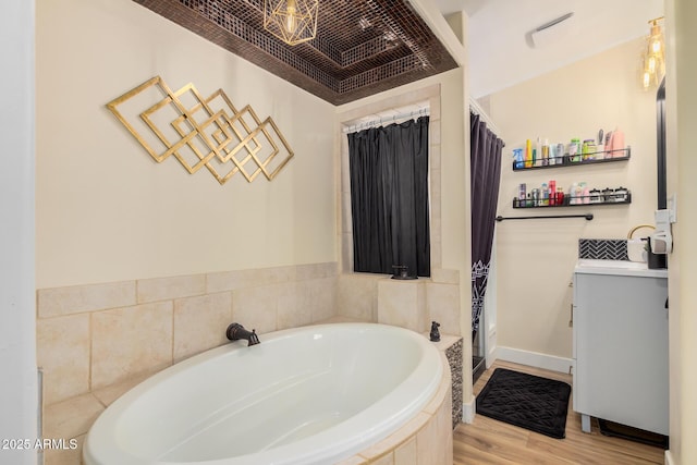 bathroom with hardwood / wood-style flooring, vanity, crown molding, and tiled tub