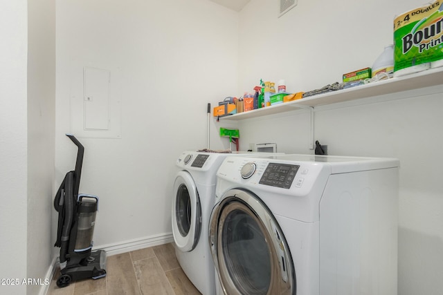 clothes washing area featuring independent washer and dryer, electric panel, laundry area, baseboards, and wood tiled floor