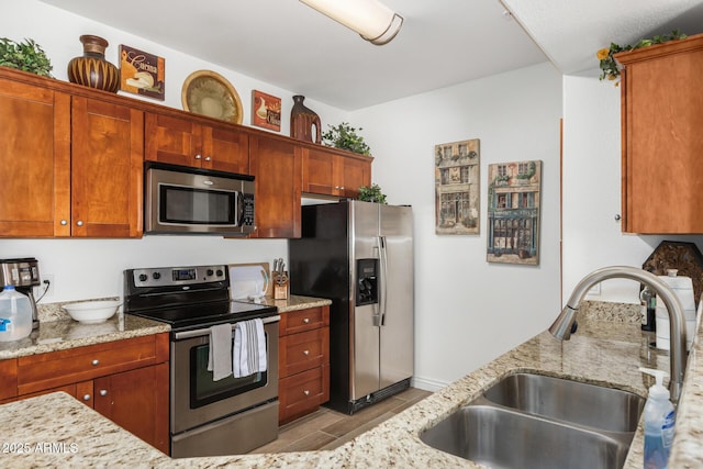 kitchen with light stone countertops, stainless steel appliances, and a sink