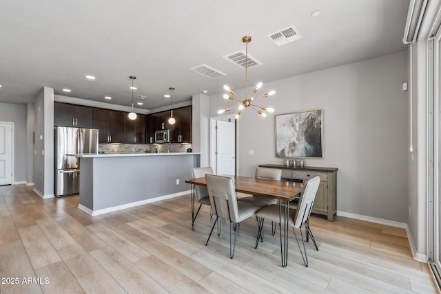 dining space featuring a chandelier, visible vents, and light wood finished floors