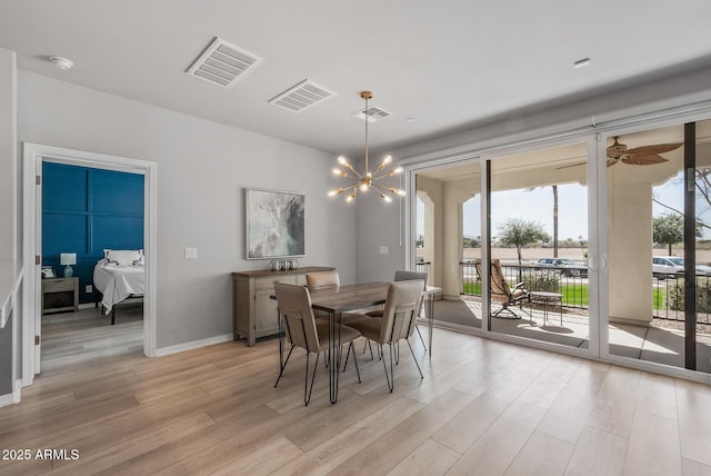 dining space with light wood-type flooring, baseboards, visible vents, and a chandelier