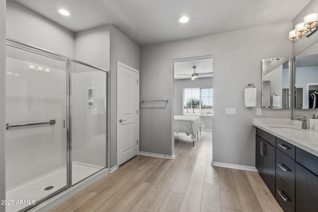 bathroom with a stall shower, wood finished floors, vanity, and baseboards