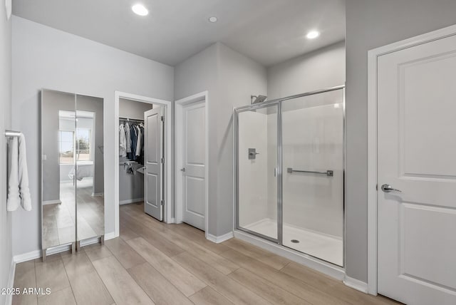 full bathroom with recessed lighting, a shower stall, baseboards, and wood finished floors