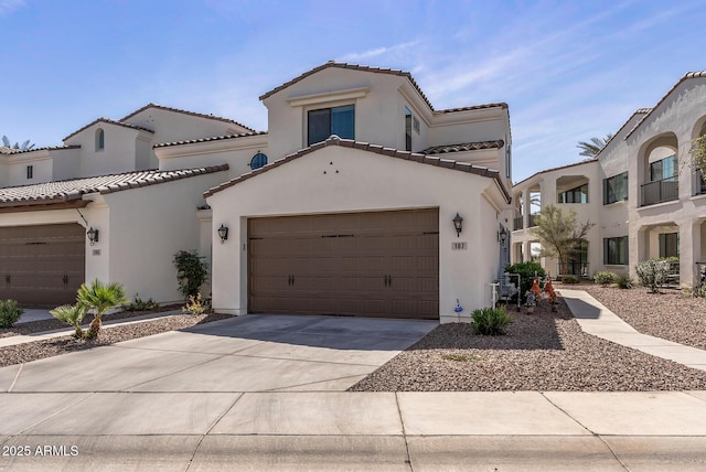 mediterranean / spanish-style house featuring a garage, concrete driveway, a tiled roof, and stucco siding