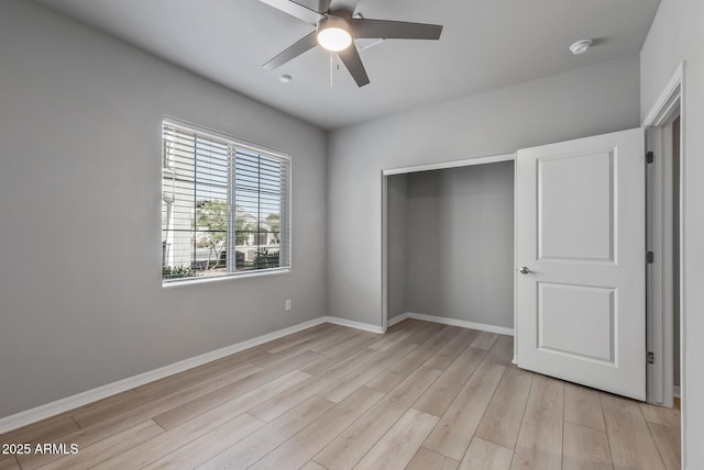 unfurnished bedroom with ceiling fan, light wood finished floors, a closet, and baseboards